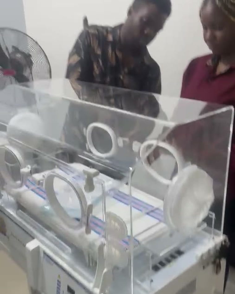 A neonatal incubator being checked over by clinical staff on the ward